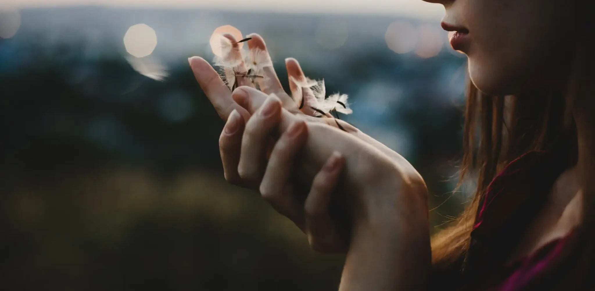Female portrait. Nature. Pretty woman plays with dandelion standing before the sunset view
